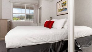 Un dormitorio con una cama grande, una ventana con cortinas, un aparador y un cuadro en la pared.