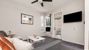 Una sala de estar con un sofá gris, una mesa de centro blanca y un cuadro en la pared.