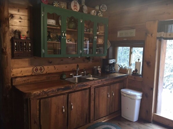 A rustic kitchen with wooden cabinets, a sink, and a window. - Cozy Cabin located in the heart of the Black Hills, but close to Deadwood & Lead (Central City)