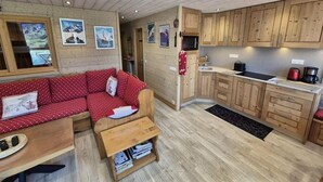 A compact living space with a red polka-dotted sofa, wooden cabinets, and a small kitchen area. - 150m from resort center, 3rd floor, view lake, balcony, tv, ski locker, 40m², Tignes (Tignes)