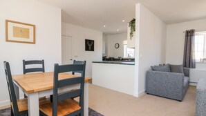A modern apartment with a dining area, kitchen, and living room. - 1 Marsh Gardens (Minehead)