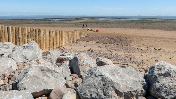 A beach with a wooden fence, large rocks, and a distant view of the sea. - 1 Marsh Gardens (Minehead)