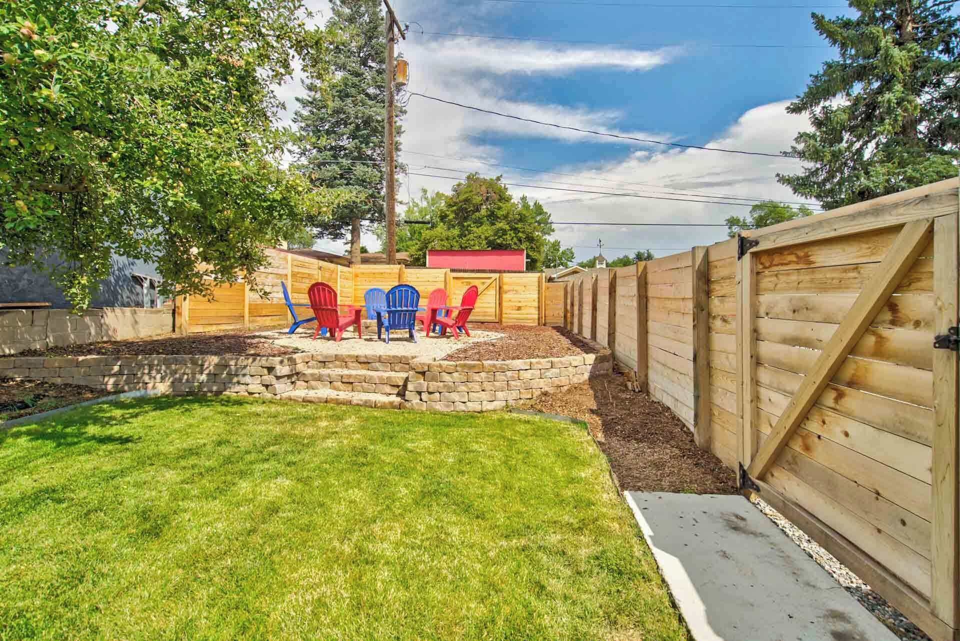 A backyard with a wooden fence, a stone retaining wall, and a grassy lawn.