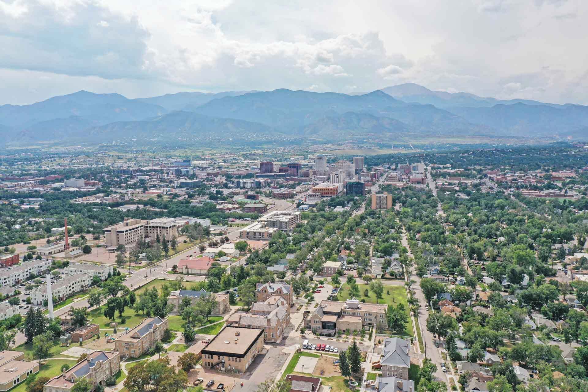 An aerial view of a city with a mix of residential and commercial buildings, surrounded by mountains.
