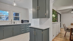 A modern kitchen with grey cabinets, white countertops, and a built-in microwave. - Sheridan Wildflower! Downtown Family Fun w/Firepit (Colorado Springs)