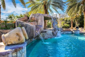 Ein Pool mit Wasserfall, umgeben von Palmen und Felsen.