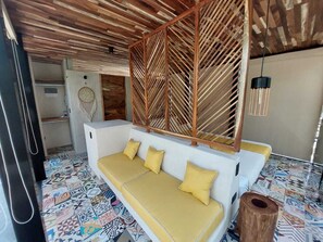 A room with a patterned floor, a white sofa with yellow cushions, a wooden ceiling, and a hanging light fixture. - Reflective Jungle Treehouse next door to renowned yoga studio Holistika (Tulum)