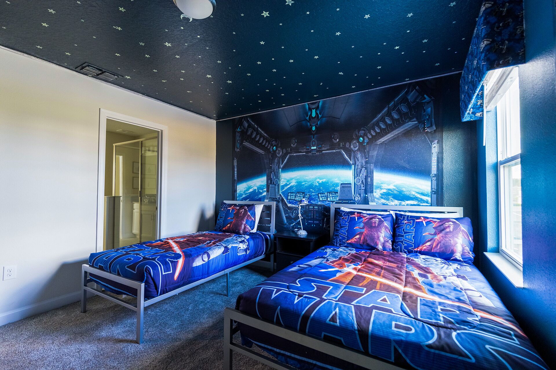 A bedroom with two beds, a starry ceiling, and a large window with a view of Earth.