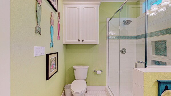 A bathroom with a toilet, a shower, and a cabinet.
