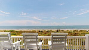 Eine Terrasse mit weißen Stühlen mit Blick auf einen Strand.