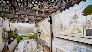 A cozy outdoor seating area with wicker furniture, a glass table, and hanging lanterns. - Riad Nolita & Spa Kasbah (Marrakech)