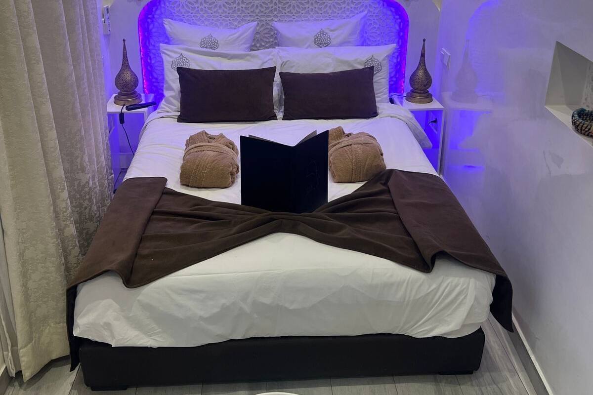 Une chambre moderne avec un grand lit, des coussins décoratifs et un design de plafond original.