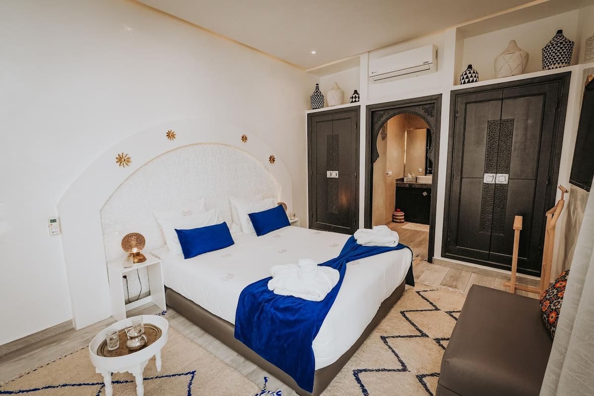 Une chambre d’hôtel avec un grand lit, une petite table de chevet, une chaise et une armoire.