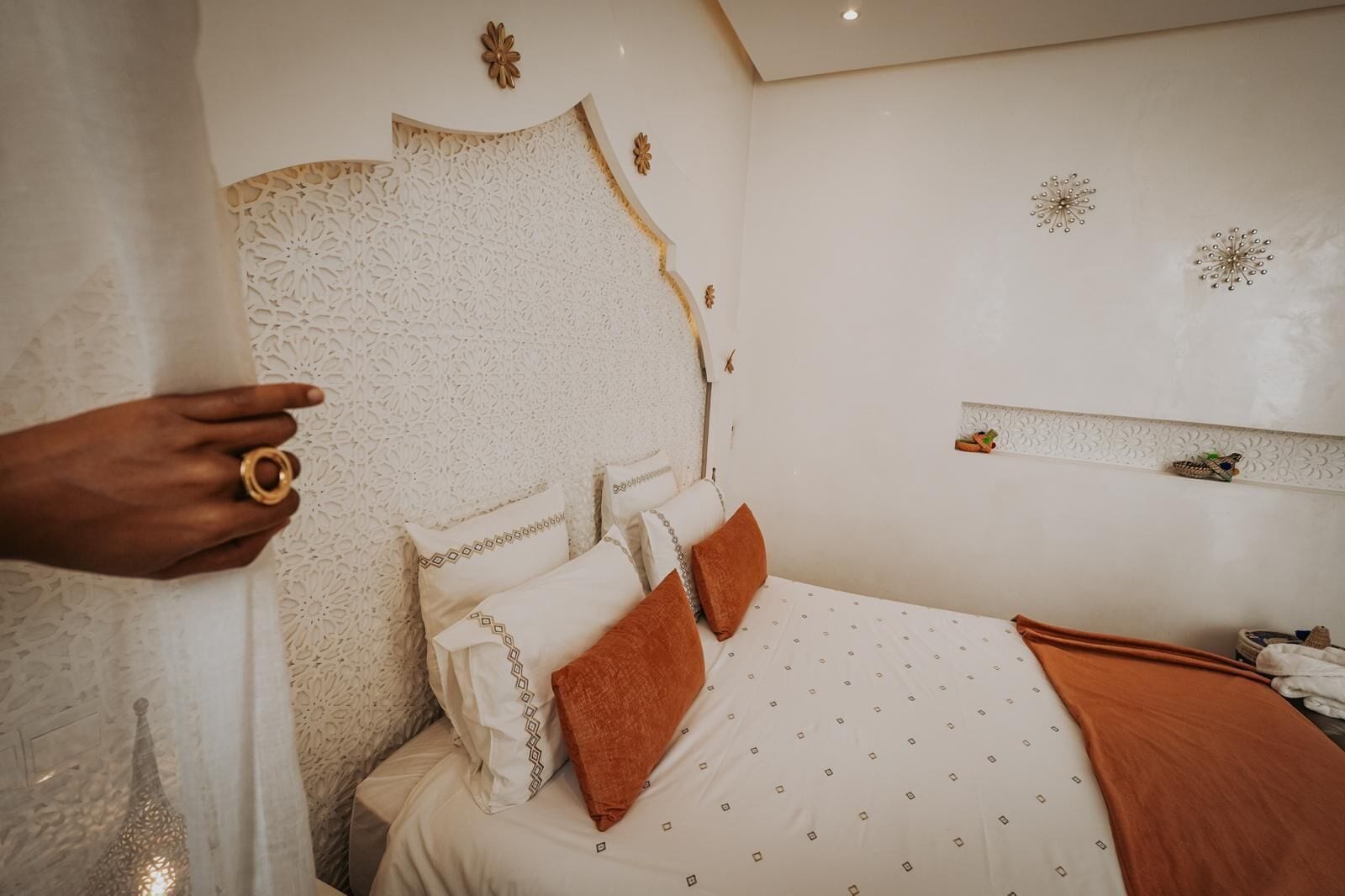 Um quarto com cama, almofadas e cabeceira decorativa.