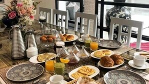 A breakfast table set with various dishes, including pastries and drinks, in a room with large windows and a view of the outside. - Riad Nolita & Spa Kasbah (Marrakech)