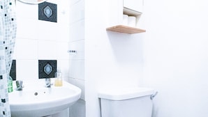 Un baño con un lavamanos blanco, un inodoro y un estante pequeño sobre el inodoro.