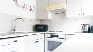 Una cocina compacta equipada con lavadora, microondas, horno y lavaplatos.
