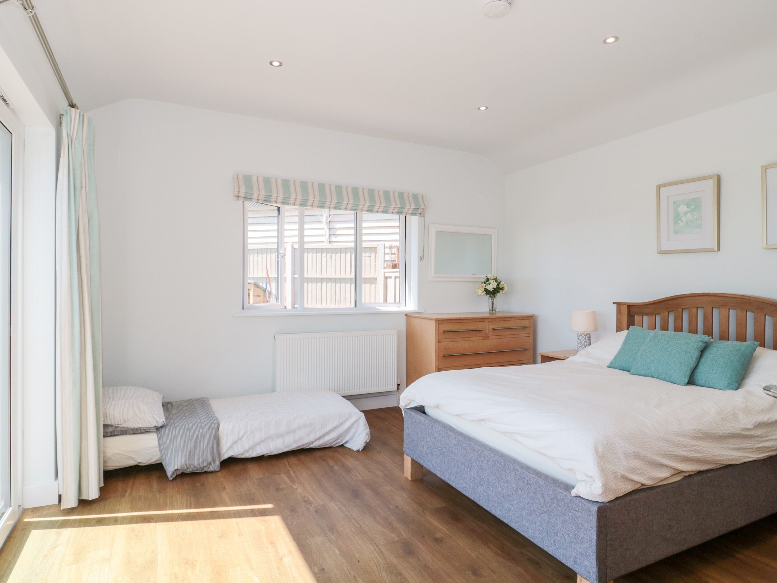 Un dormitorio con cama, cómoda, ventana y radiador.
