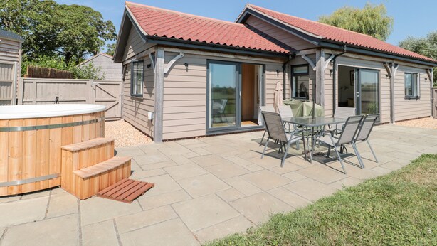A house with a patio, a hot tub, and a covered outdoor seating area. - Robins Corner (Weston-super-Mare)