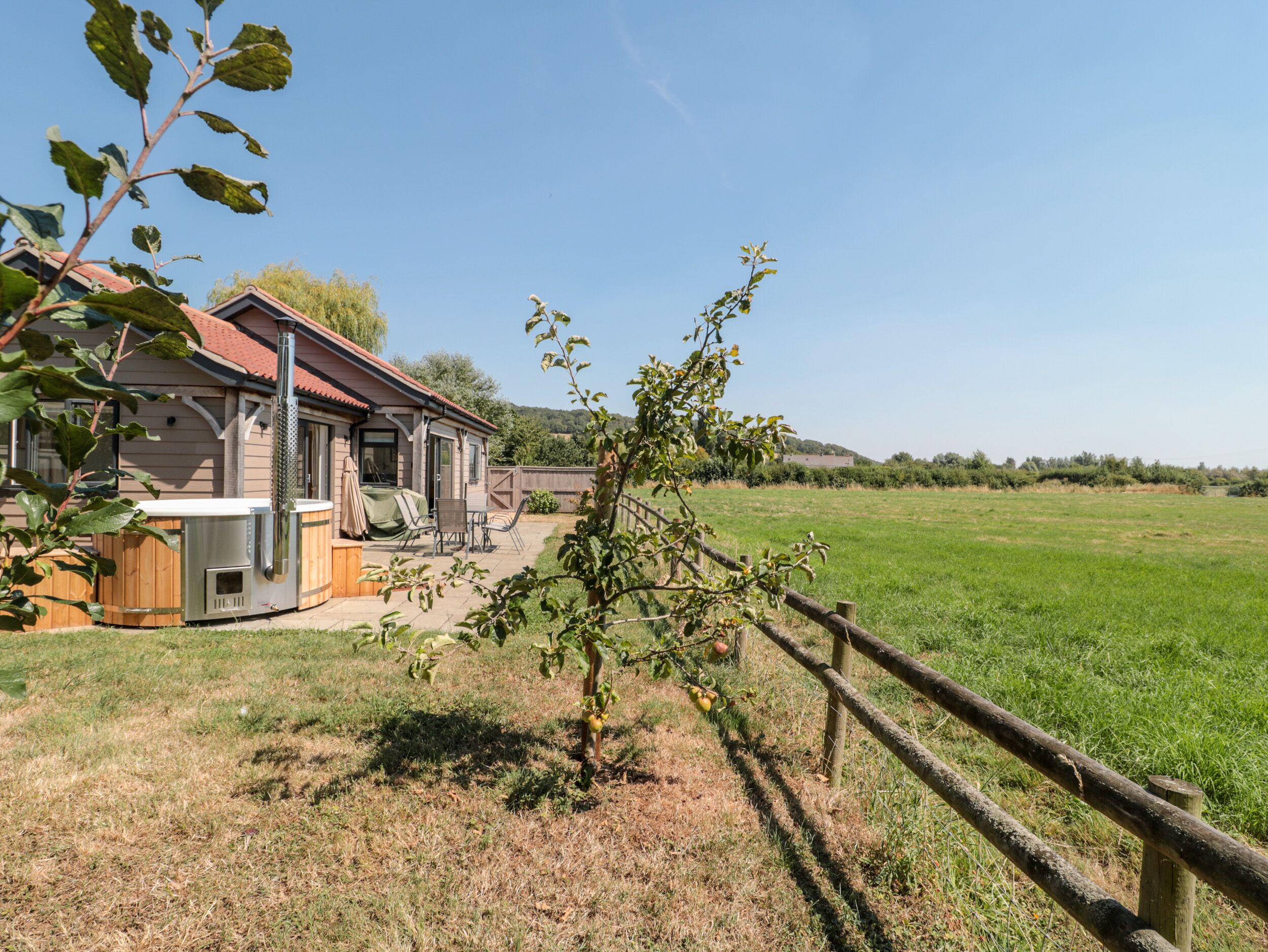 A house with a patio area, a small deck, and a fenced yard.