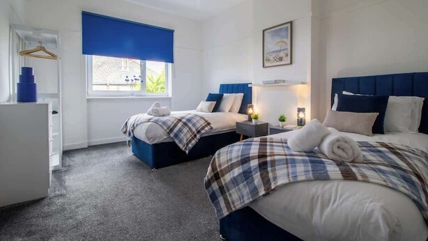 A hotel room with two beds, a desk, a dresser, and a window with a view. - Bella House Fresh 3 Bed Apt in Glasgow  Sleeps 5 (Glasgow City)