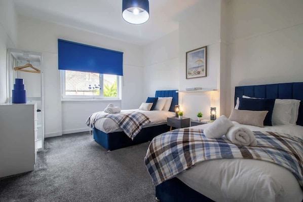 Ein Hotelzimmer mit zwei Betten, einem Schreibtisch, einer Kommode und einem Fenster mit Blick.