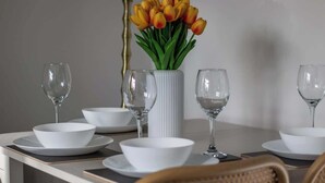 A dining table set with white bowls, wine glasses, and a vase with yellow tulips. - Bella House Fresh 3 Bed Apt in Glasgow  Sleeps 5 (Glasgow City)