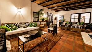 A spacious living area with a high ceiling, wicker furniture, and a patterned rug. - Fairview House (Keurboomstrand)