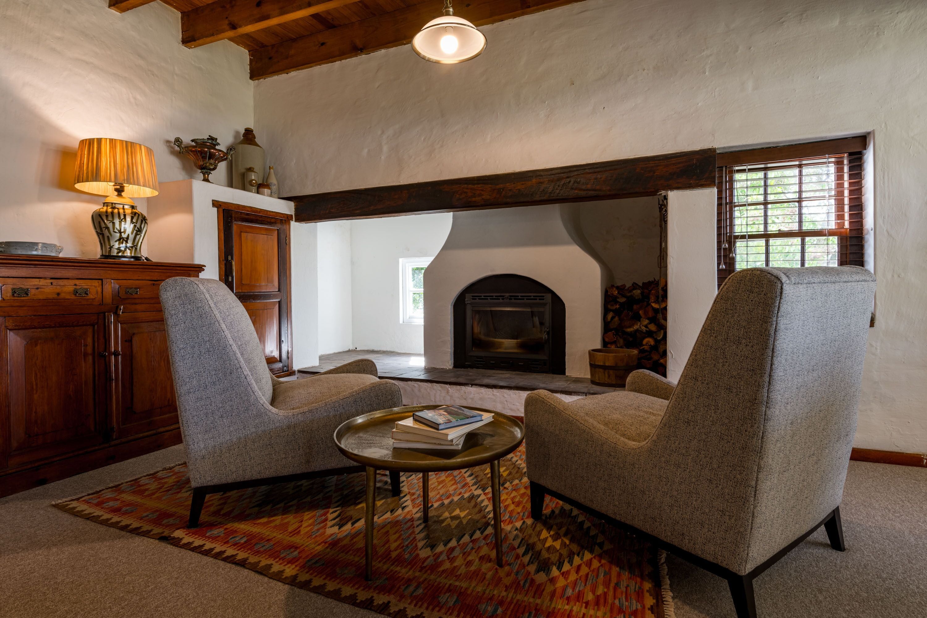 A living room with two armchairs, a coffee table, a fireplace, and a wooden ceiling.