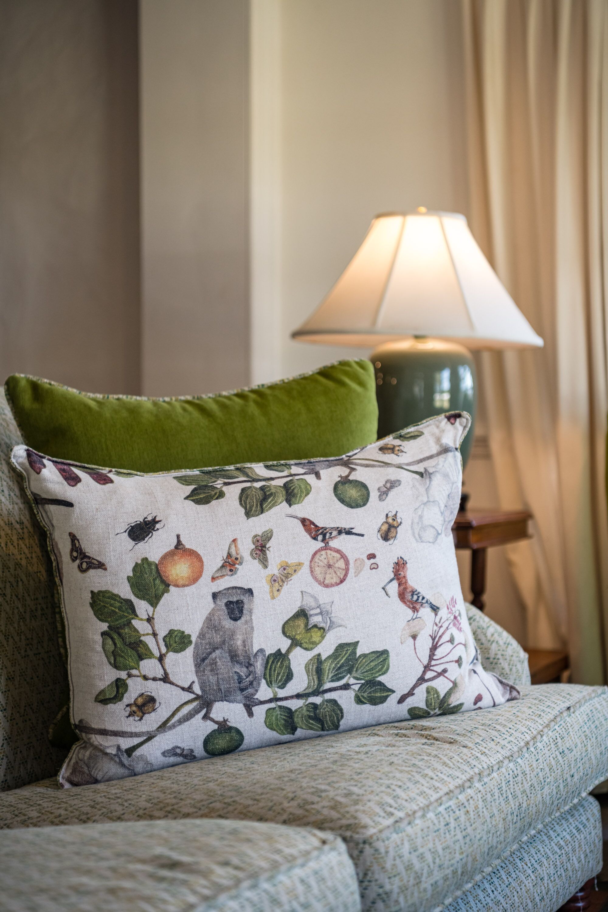 A sofa with a patterned pillow and a green accent pillow.