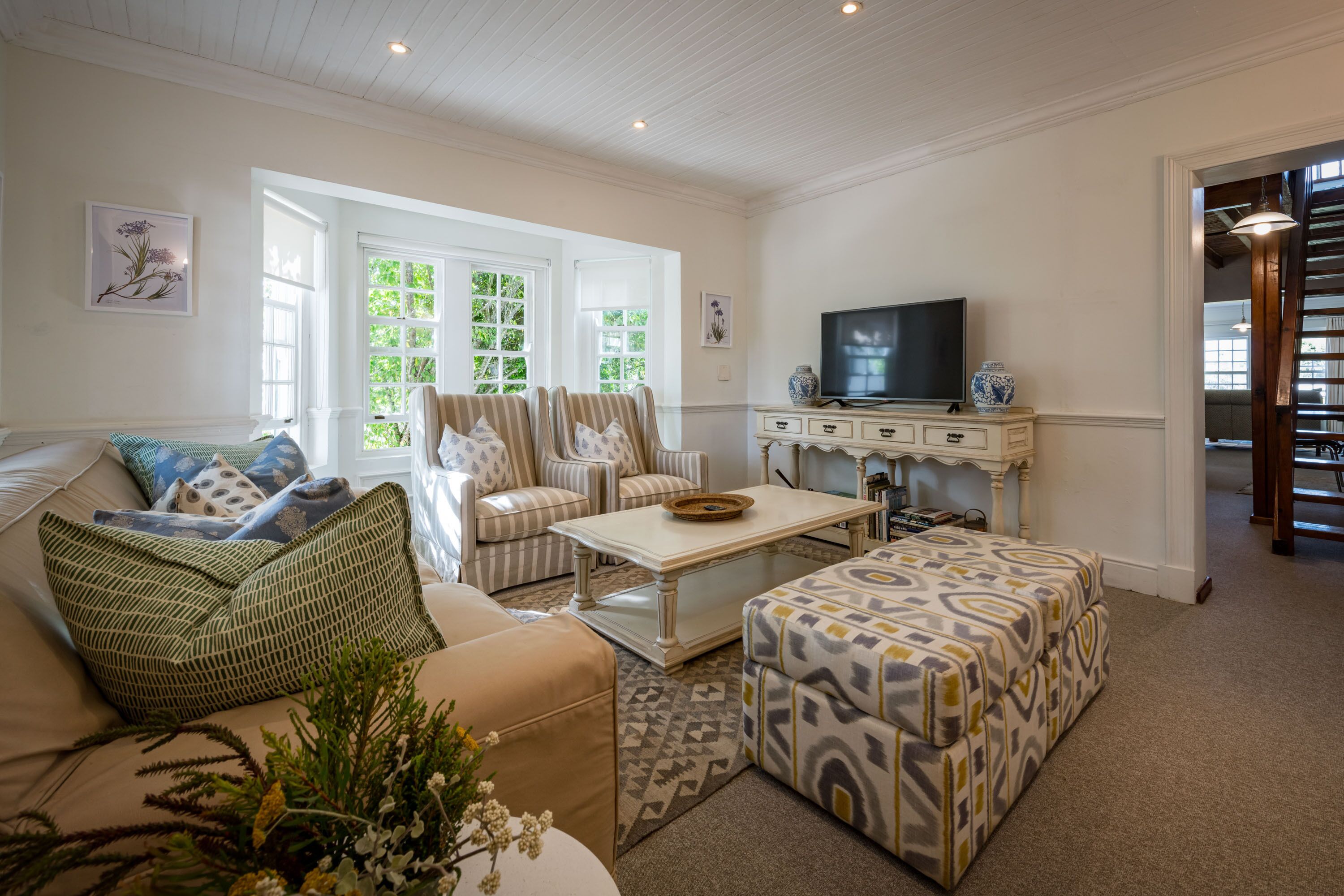 Amplia sala de estar con sofá, sillones, una mesa de centro y televisor.