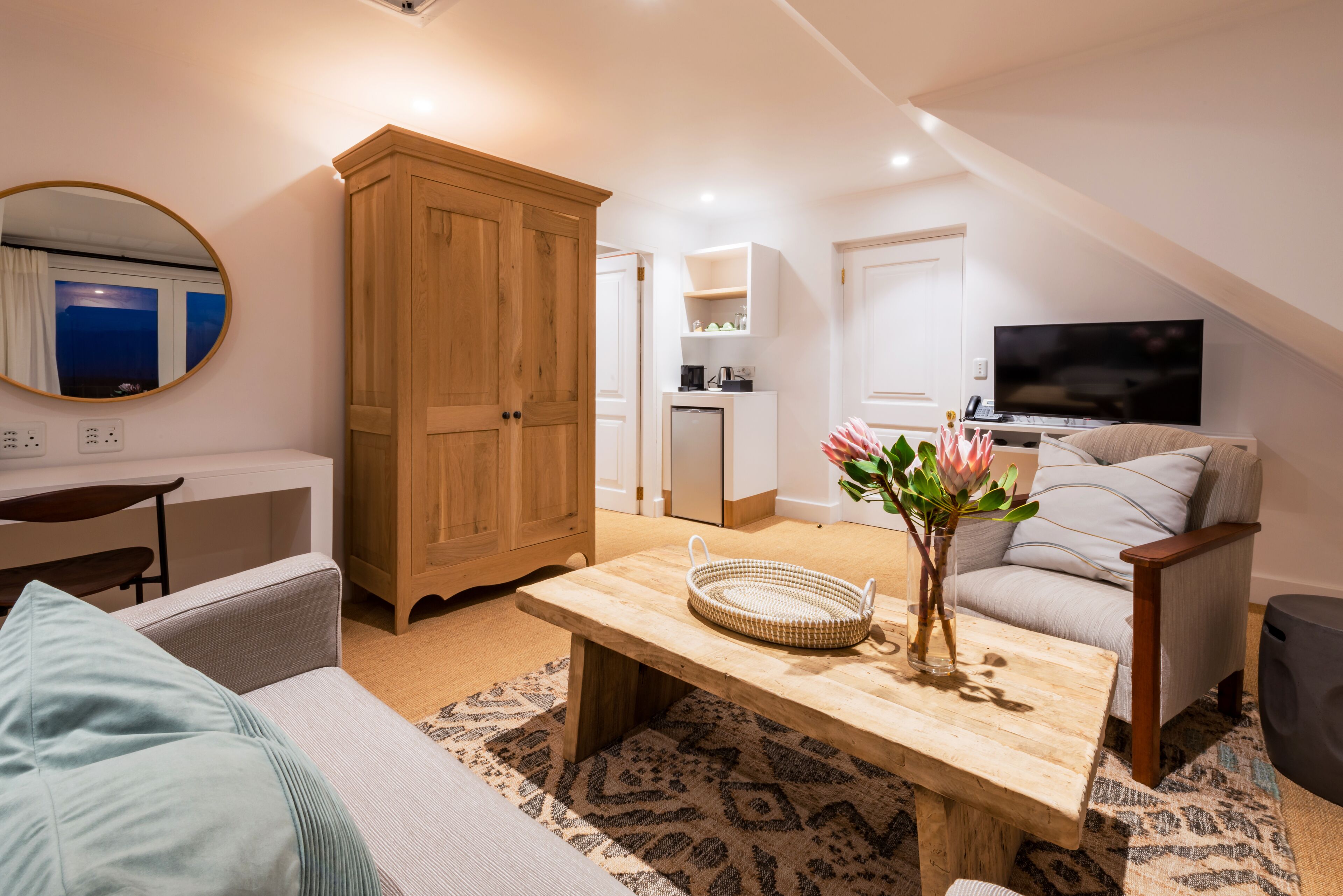 A cozy living room with a wooden cabinet, a TV, a dining table with a vase, and a sofa.