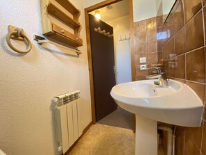 Ein Badezimmer mit Waschbecken, Holzhandtuchhalter und Heizkörper.