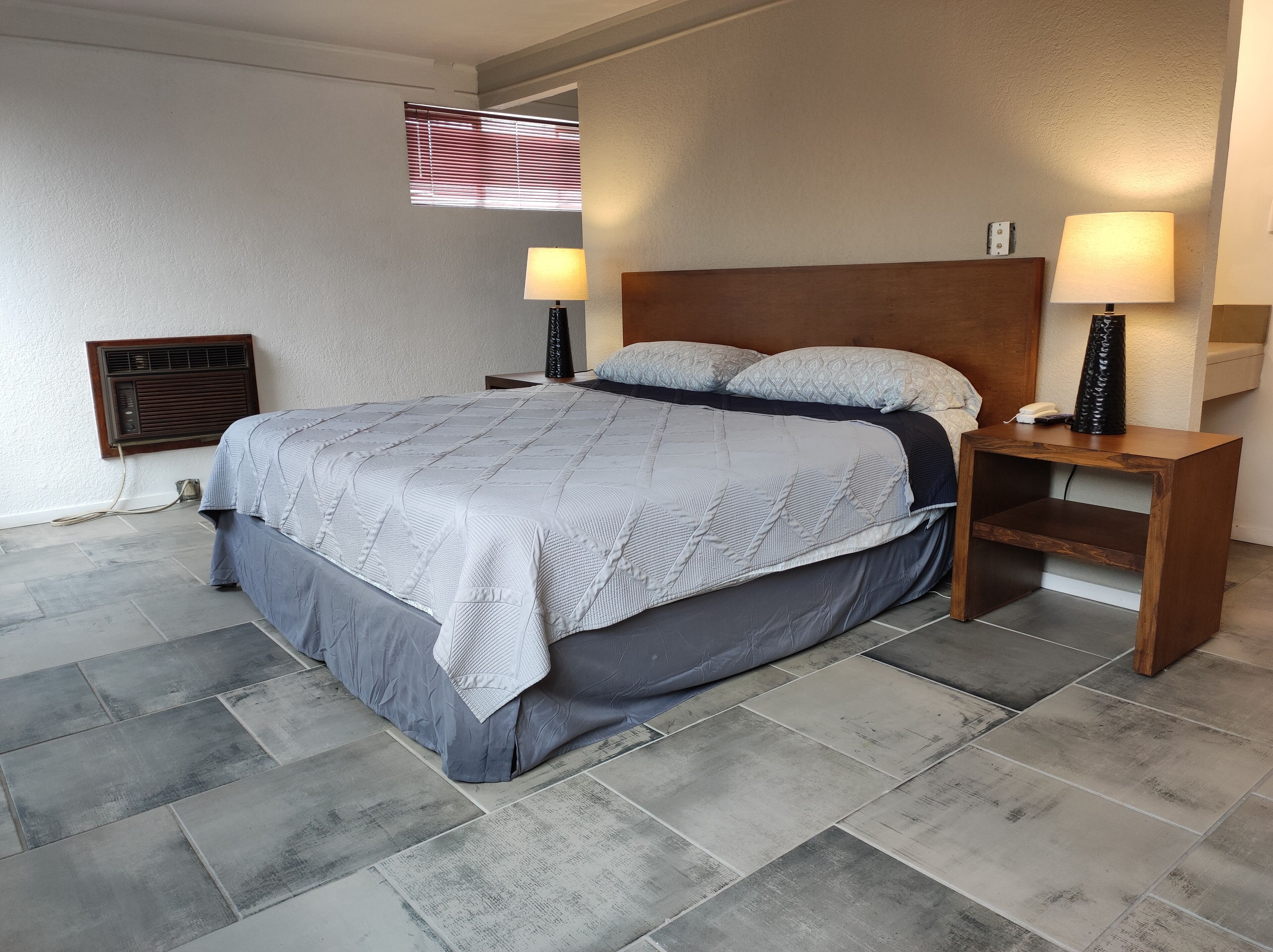 Camera da letto ordinata con un letto grande, due comodini con lampade, un termosifone a parete e una finestra con persiane.
