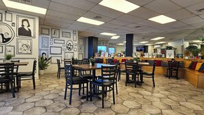 A restaurant with hexagonal tile flooring, black and white framed artwork on the walls, and a counter with a variety of seating options including tables and benches. - Hotel Maripina (Ciudad Juárez)
