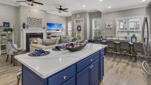 A modern kitchen with a central island, built-in cabinets, and a dining area with chairs. - Modern Beach Retreat • Hot Tub • Private Beach Access • Sleeps 10 (Miramar Beach)