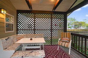 A covered porch with a white table and cushioned seating, a decorative lattice, and a view of the outdoors. - Fully Fenced, Dogs Welcome, Sleeps 10, Near MSU and Hospitals (Springfield)