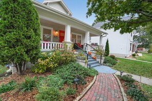 A two-story house with a front porch, a staircase, and a well-maintained garden. - Fully Fenced, Dogs Welcome, Sleeps 10, Near MSU and Hospitals (Springfield)