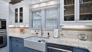 A modern kitchen with a granite countertop, stainless steel appliances, and blue cabinetry. - Fully Fenced, Dogs Welcome, Sleeps 10, Near MSU and Hospitals (Springfield)