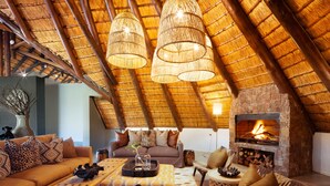 A cozy living room with a thatched roof, a fireplace, and comfortable seating. - Sungulwane Private Game Lodge (Hluhluwe)