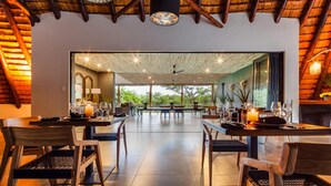 A spacious dining area with a high ceiling and natural light, featuring tables set for dining and chairs. - Sungulwane Private Game Lodge (Hluhluwe)