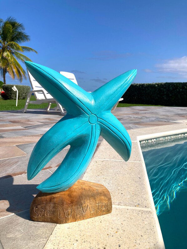 A turquoise starfish sculpture on a wooden base with "Sea La Vista" engraved on it, placed on a tiled patio by a pool. - Lux 3 Bdrm Ocean Front villa with Private pool! (Lowlands)