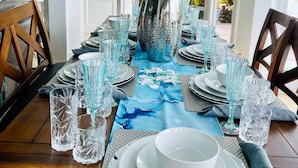 A dining area with a table set for six, featuring a blue table runner, clear glassware, and silverware. - Lux 3 Bdrm Ocean Front villa with Private pool! (Lowlands)