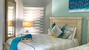 A bedroom with two beds, a ceiling fan, a large mirror, and a wall painting. - Lux 3 Bdrm Ocean Front villa with Private pool! (Lowlands)