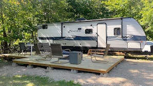A Zinger RV with a deck area featuring outdoor furniture. - Beautiful experience on Gull Lake. (Nisswa)