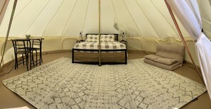 A tent with a bed, a chair, a small table, and a rug.