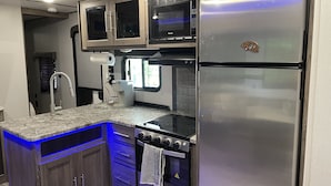 A compact kitchen with a stainless steel refrigerator, a microwave, a coffee maker, and a stove. - Beautiful experience on Gull Lake. (Nisswa)