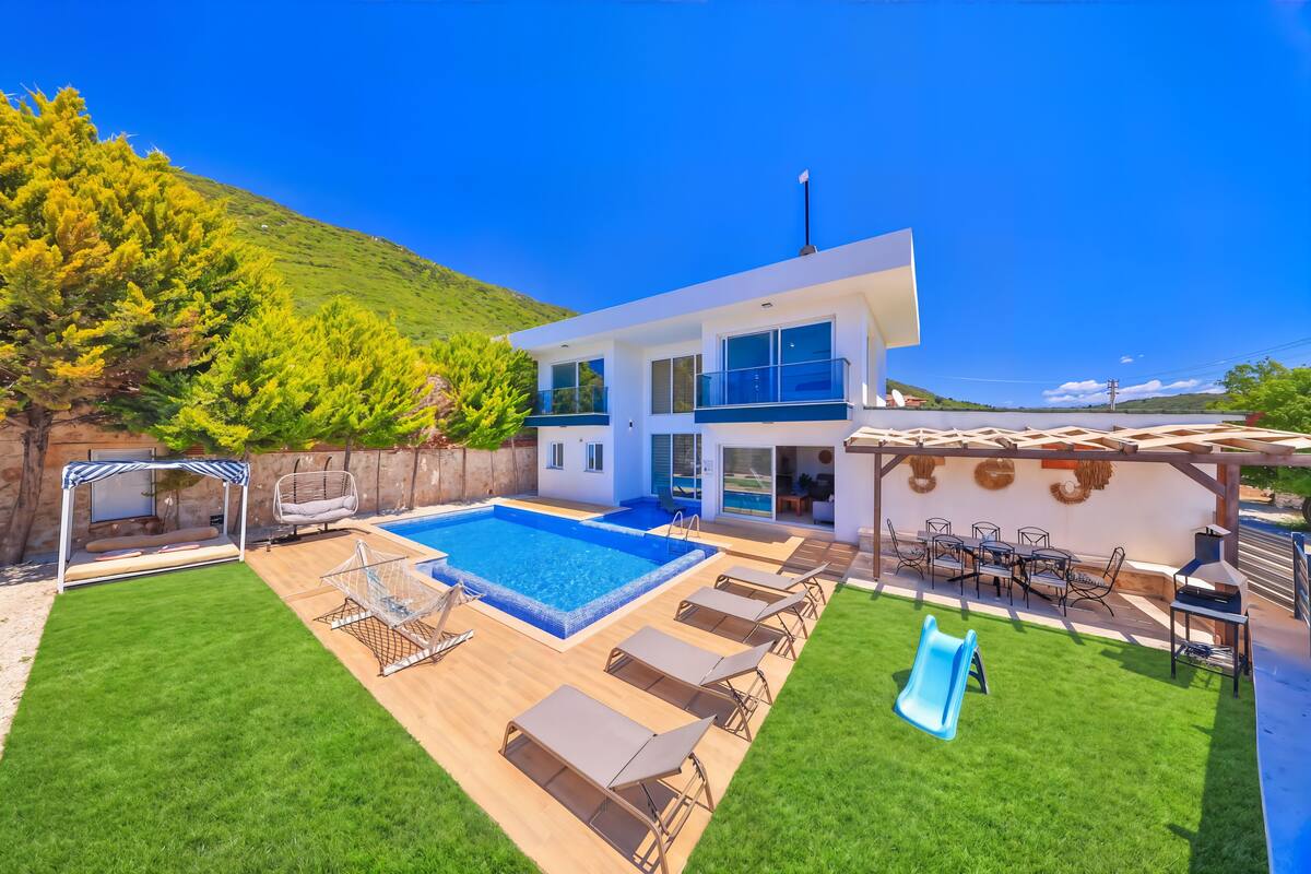 Uma casa moderna com piscina, área de estar externa e um escorrega.