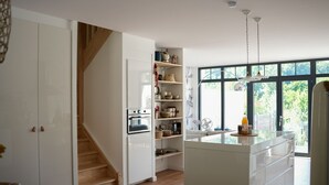 A modern kitchen with white cabinetry, a central island, and a built-in oven. - Les Hirondelles, beautiful house with garden for 7 people (Saint-Valery-sur-Somme)