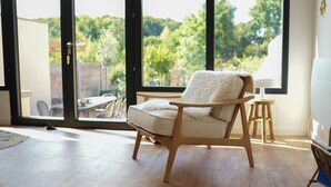A room with a large window, a wooden floor, and a chair with a fluffy white cushion. - Les Hirondelles, beautiful house with garden for 7 people (Saint-Valery-sur-Somme)